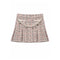 A pleated tweed mini skirt in a pink, beige, and black micro-tweed pattern, featuring a decorative cream-colored faux pearl strap across the front waistband, shown flat on a white background.