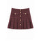 A pleated tweed mini skirt in a dark burgundy and brown woven pattern, featuring a button-up front with gold-tone buttons and two decorative button-flap pockets on the front.