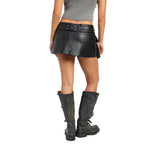 A model shown from the back wearing a black textured faux-leather wrap mini skirt with a matching belt, paired with distressed black knee-high boots and a gray ribbed crop top, against a plain white background.