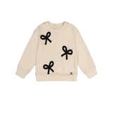 An off-white ribbed knit long-sleeve sweatshirt with three black bow appliqués on the front, displayed flat against a solid white background.