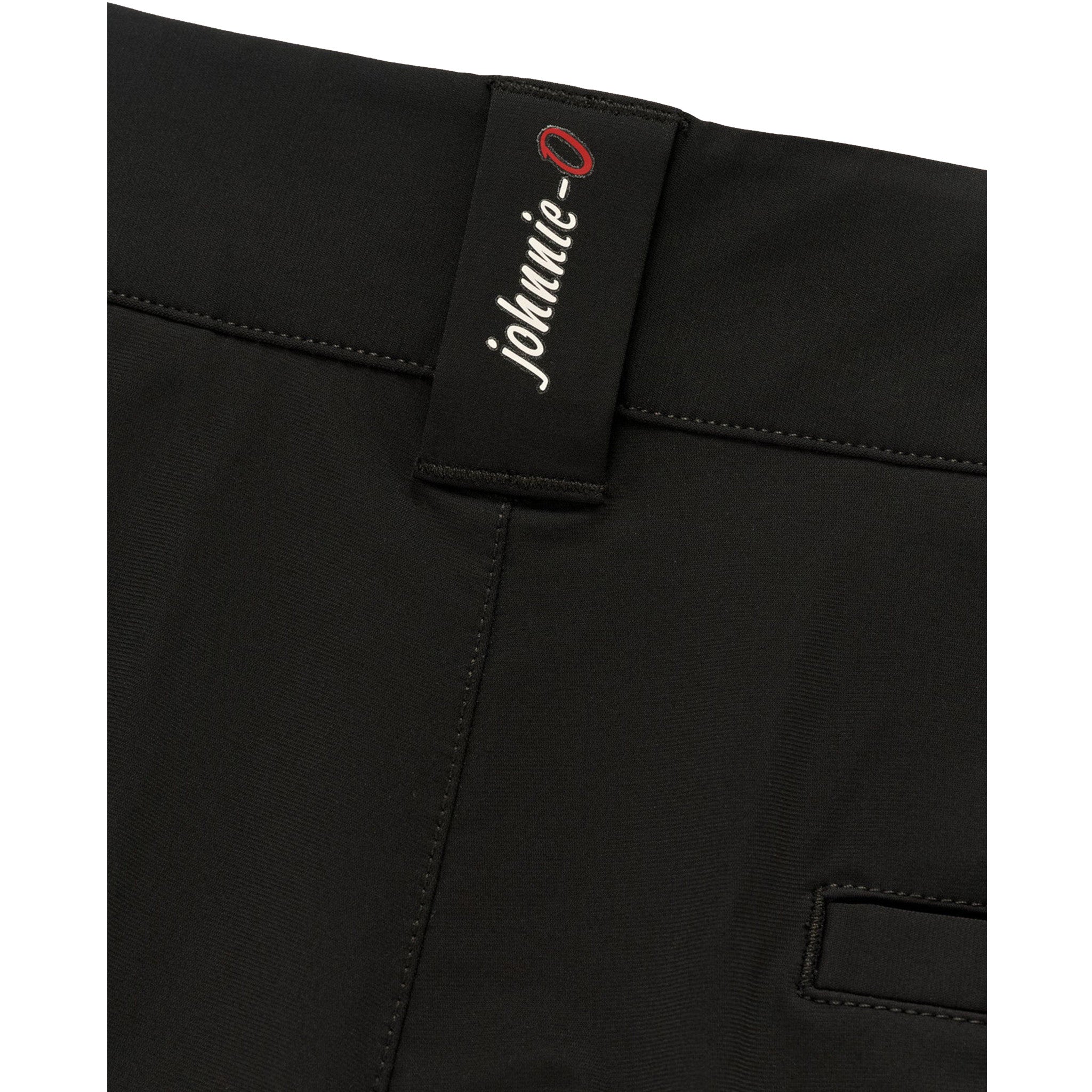 Close-up of black trousers showing the waistband and a black brand tab with white 'johnnie-0' script and a red circular accent, on a white background.
