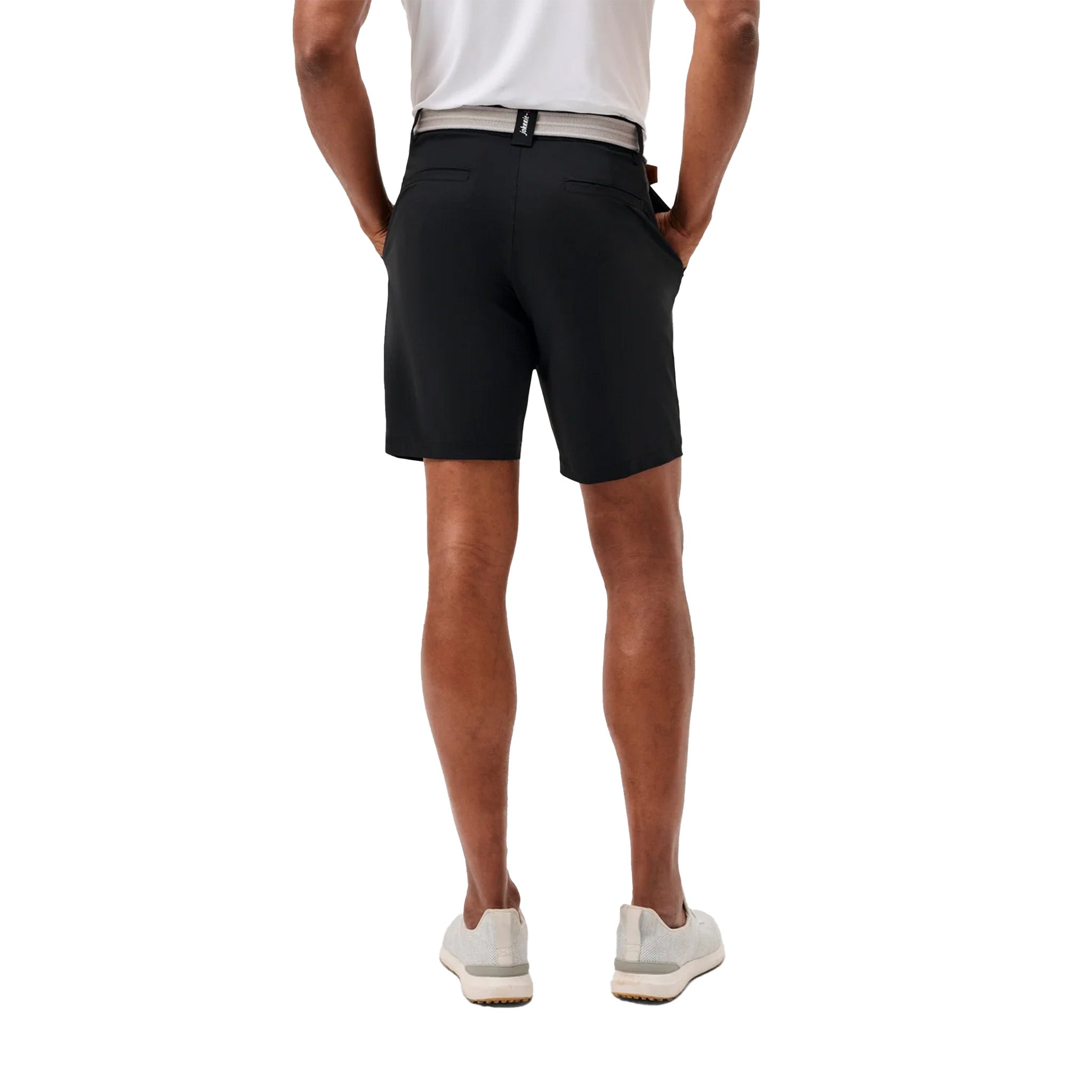 Rear view of a man wearing black athletic shorts, a white shirt, and white sneakers against a plain white background.