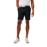 A man wearing black golf shorts, a white polo shirt, a brown leather belt, and white golf shoes, shown from the waist down on a solid white background.