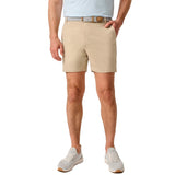 A man wearing beige chino shorts with a patterned belt, a light blue t-shirt, and white sneakers, shown from the waist down on a white background.
