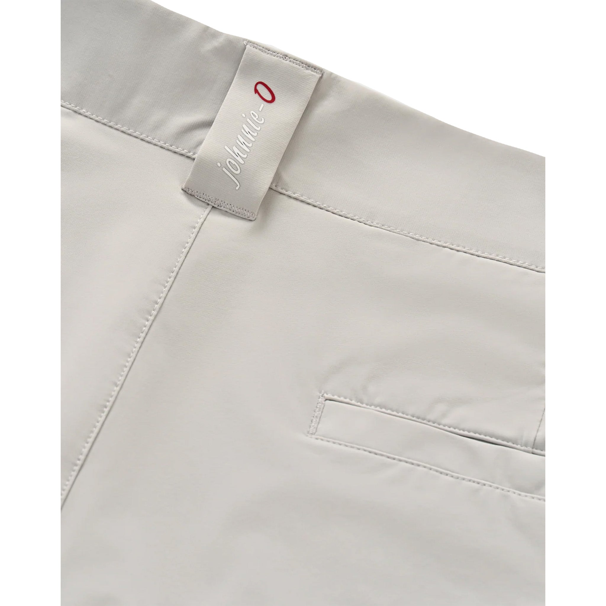 Close-up of light gray shorts showing the waistband, a fabric brand tag reading 'johnnie o' with a red 'O', and part of a side pocket.