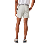 A man shown from the back wearing light beige golf shorts, a white polo shirt, and golf shoes against a solid white background.