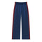 A pair of navy blue wide-leg athletic pants with red and white side stripes, featuring an elastic waistband, shown against a plain white background.