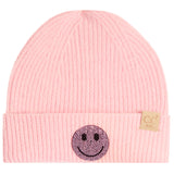 A light pink ribbed knit beanie hat for kids, featuring a black and pink rhinestone smiley face patch on the front cuff and a small tan brand tag on the side.