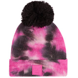 A pink and black tie-dye knit beanie with a large black pom-pom on top and a pink stitched logo patch on the cuff. The patch reads 'CC.
