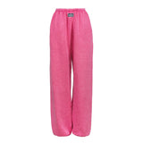 Bright pink wide-leg sweatpants with an elastic waistband and a small black brand patch on the front, shown against a plain white background.