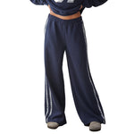 A person wearing loose navy wide-leg sweatpants with lace side stripes shown against a plain white studio background.