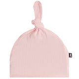 A light pink crinkle gauze baby beanie hat with a knotted top and a small black brand tag on the side, shown against a plain white background.