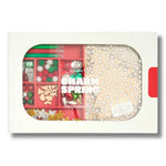 A packaged craft kit labeled 'CHARM SPRING The Christmas Kit' in a white box with a clear front window showing holiday-themed craft supplies inside, including red compartments and a beige sequined sheet.