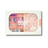 Enchanted Kit 'charm SPRING' Create Kit in a white box with a clear oval window showing pink and pastel beads, sequins, small embellishments, and decorative pieces.