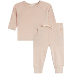 A two-piece baby clothing set in a soft, pale blush pink. The set includes a long-sleeve raglan top with a crew neck and matching jogger pants with side pockets and an elastic drawstring waist.
