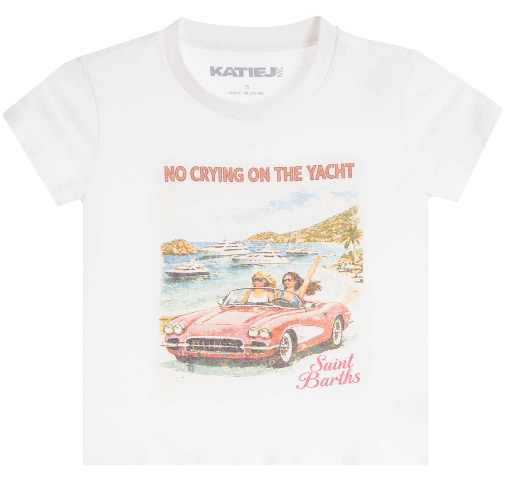 A white short-sleeve graphic t-shirt by Katie J. The front features a colorful illustration of a pink convertible car with two women on a beach, accompanied by the text 'NO CRYING ON THE YACHT' and 'Saint Barth'.