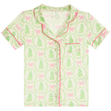A short-sleeve button-front pajama top with a green and pink holiday print featuring wreaths, Christmas trees, and bows, shown flat against a white background.
