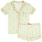A two-piece pajama set featuring a short-sleeve button-front top and matching shorts in a light green and white holiday pattern with pink bows and green trees, accented with pink piping.