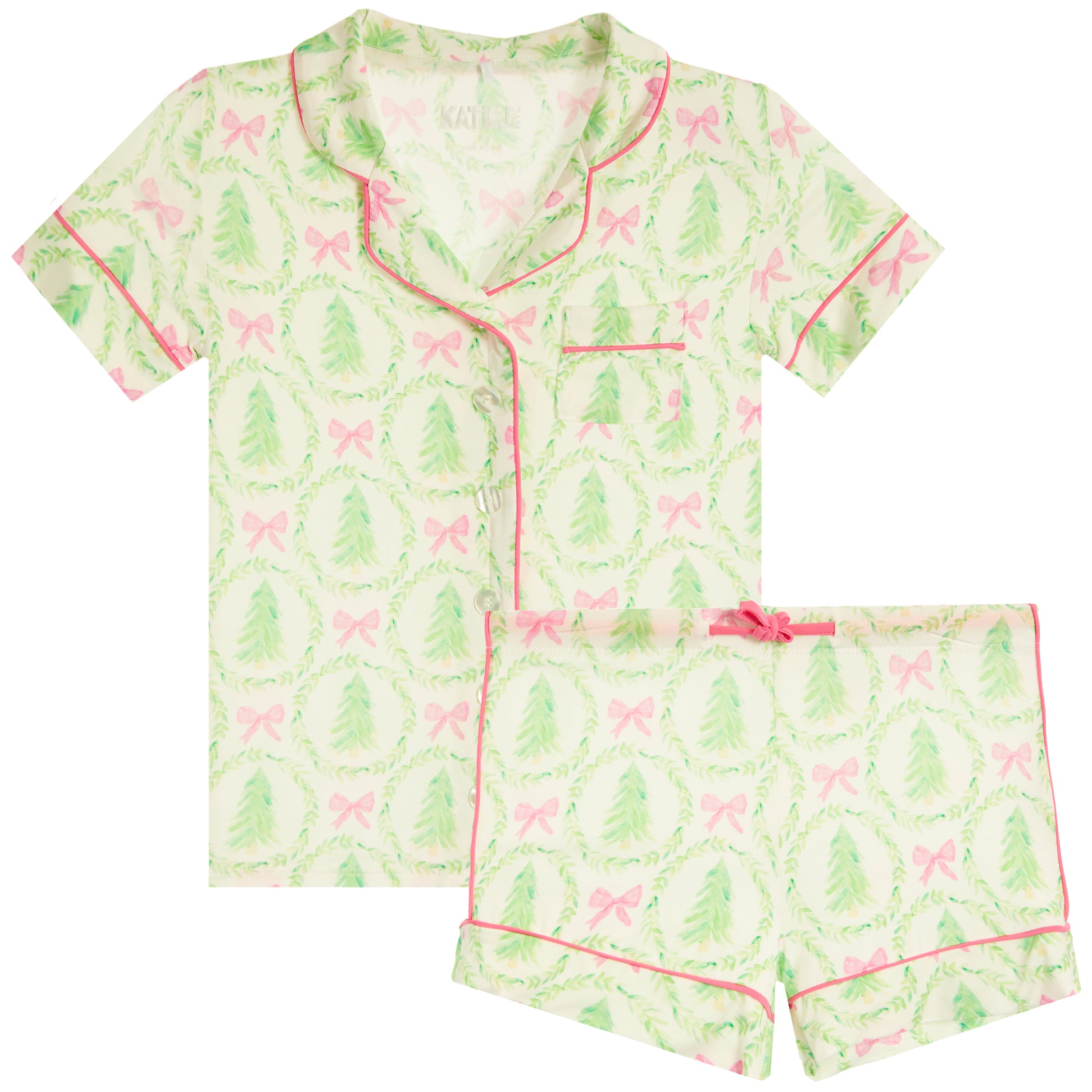 A two-piece pajama set featuring a short-sleeve button-front top and matching shorts in a light green and white holiday pattern with pink bows and green trees, accented with pink piping.