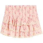 A light pink tiered skirt with a delicate floral print, featuring an elastic smocked waistband and layered ruffles finished with cream lace trim.