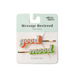 Olivia Moss 'Message Recieved' hair pins set, featuring two gold bobby pins with colorful enamel lettering that reads 'good mood' on a white and mint display card.