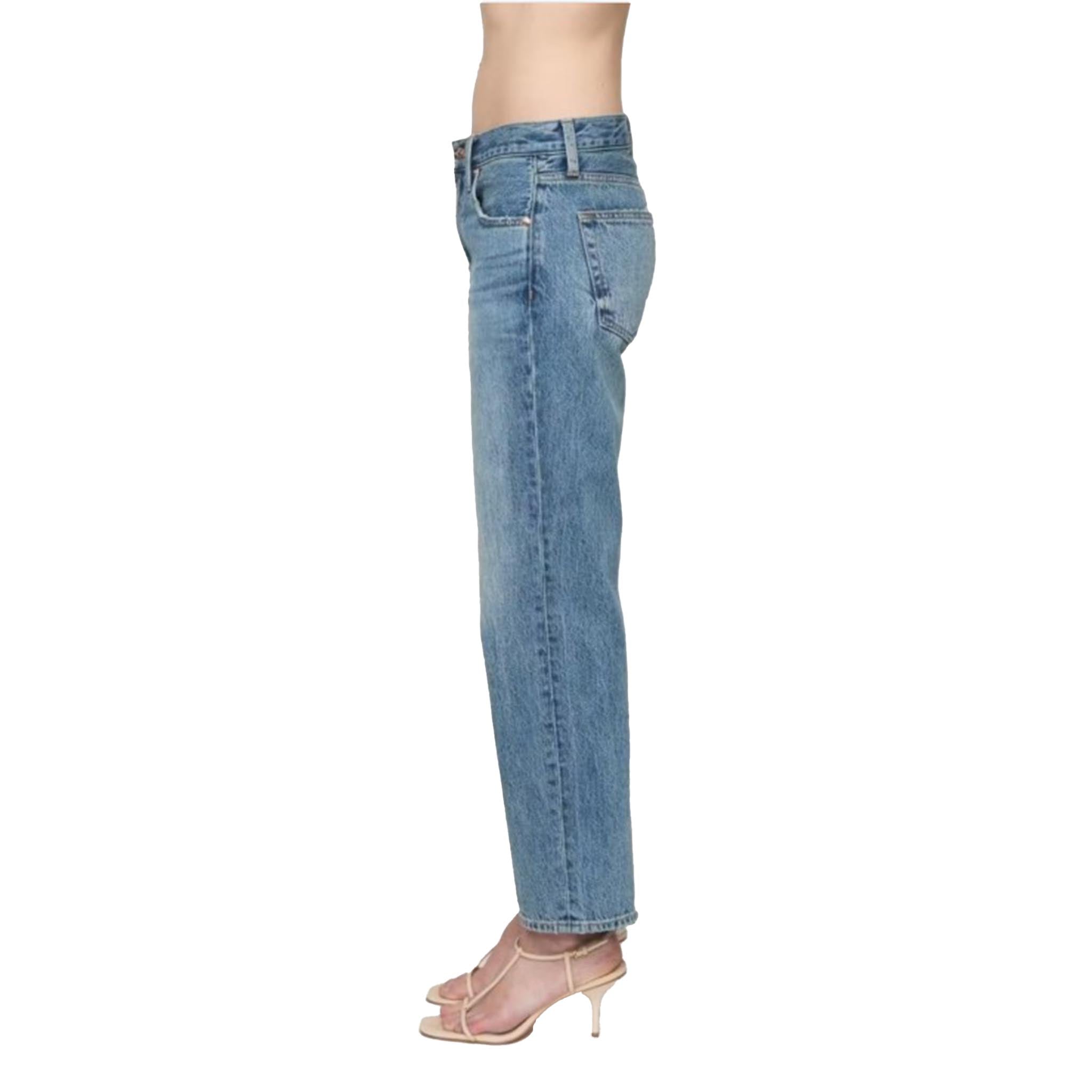 A side profile view of a model wearing light blue straight-leg denim jeans and clear high-heeled sandals against a plain white background.