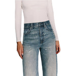 A model wearing high-waisted, wide-leg blue jeans covered in sparkling rhinestones, paired with a light beige long-sleeve top, shown against a plain white background.