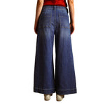 Rear view of a person wearing dark blue wide-leg denim jeans with a red top and white sneakers, isolated on a white background.