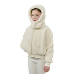 A child wearing a cream-colored sherpa fleece hooded jacket with a high collar and white pants, photographed against a solid white background.