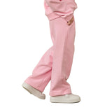 A person wearing light pink sweatpants and white sneakers, shown from the waist down in a side-profile pose against a plain white background.