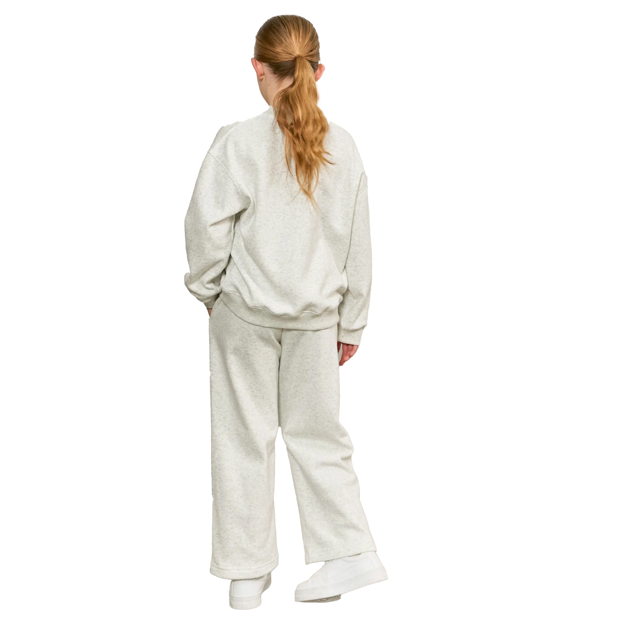A woman viewed from behind wearing a matching light heather gray sweatshirt and wide-leg sweatpants set, paired with white sneakers, against a plain white background.