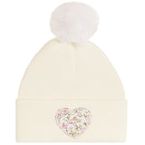 An off-white ribbed knit pom-pom beanie featuring a pink and green floral heart patch on the front cuff.