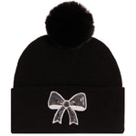A black knit pom-pom beanie featuring a white sequined bow embellishment on the front cuff, set against a plain white background.