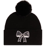 A black knit pom-pom beanie featuring a white sequined bow embellishment on the front cuff, set against a plain white background.