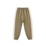 A pair of children's jogger pants in a muted khaki green, featuring cream-colored side panels and elastic cuffs, shown against a plain white background.