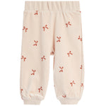 A pair of cream-colored fleece pants with a repeating pattern of small red bows, featuring an elastic waistband and ribbed ankle cuffs.