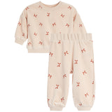 A two-piece children's pajama set featuring a long-sleeve top and matching pants in a light cream color with a small red bow print, displayed on a solid white background.
