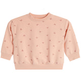 A light peach-pink long-sleeve baby's crewneck sweatshirt with a repeating pattern of small pink hearts, shown flat against a white background.