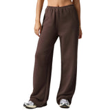 A person wearing loose, wide-leg brown sweatpants with an elastic waistband, shown from the torso down against a plain white background.