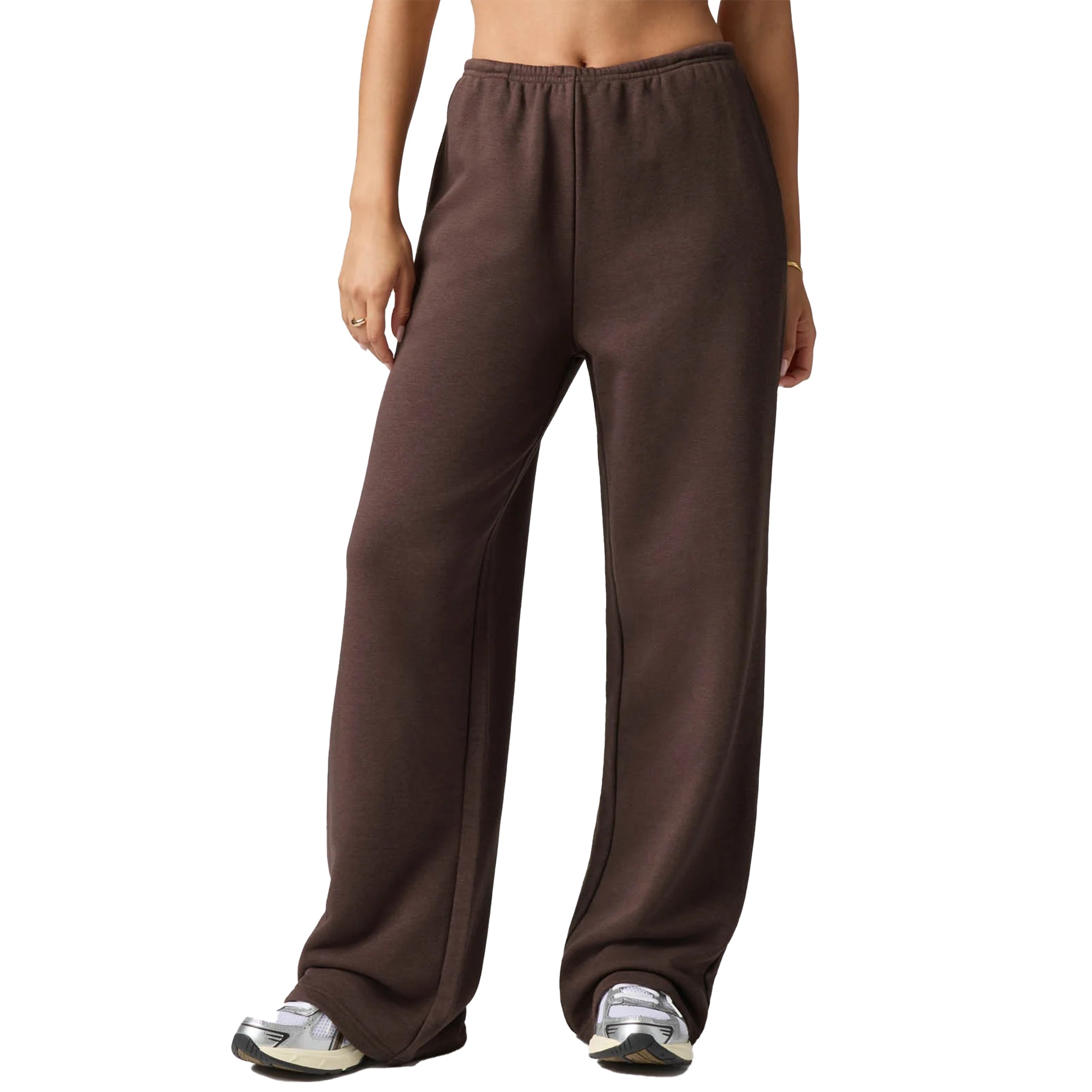 A person wearing loose, wide-leg brown sweatpants with an elastic waistband, shown from the torso down against a plain white background.