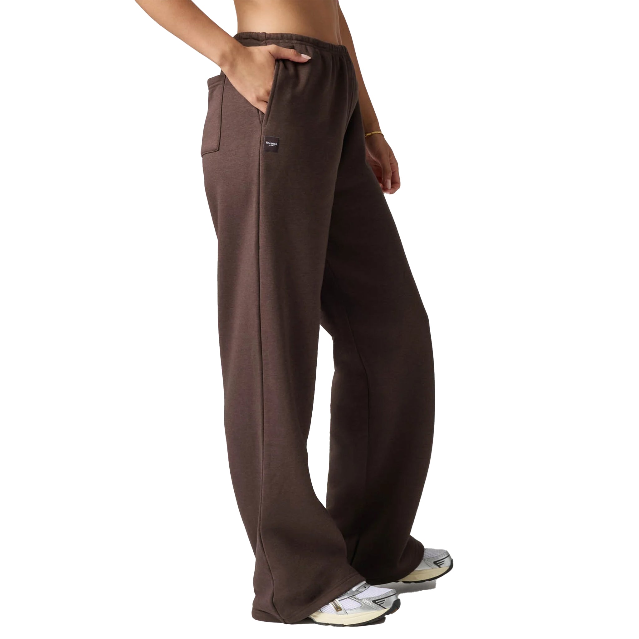 A person wearing dark brown wide-leg sweatpants with side pockets, shown from the waist down against a plain white background.