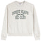 A light heather gray crewneck sweatshirt featuring the text 'BUNNY SLOPE SKI CLUB' in dark green varsity-style lettering with crossed skis and a bunny logo on the chest.