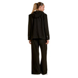 A woman shown from the back wearing a black hooded blazer and matching wide-leg trousers against a plain white studio background.
