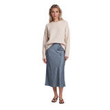 A woman modeling a cream knit sweater and a slate blue satin midi skirt against a plain white background.