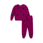 A kids' two-piece sweatshirt and jogger pants set in magenta, featuring black star motifs printed all over, displayed on a clean white background.
