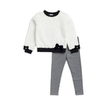 A children's two-piece outfit set featuring a fuzzy off-white long-sleeve top with black trim and bow details on the cuffs and hem, paired with black and white gingham checkered pants, shown against a plain white background.