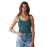 A woman modeling a teal ribbed tank top paired with light-wash blue jeans against a plain white background.