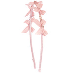 A light blush headband decorated with three matching satin bows and small gold rhinestone accents, shown against a plain white background.