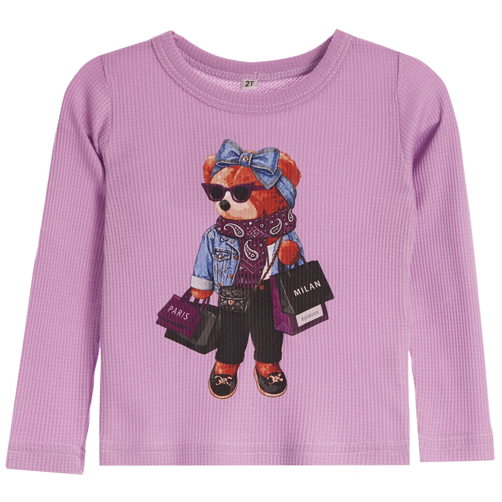 A lavender long-sleeve waffle-knit top for kids, featuring a central graphic of a teddy bear dressed in denim and holding shopping bags with 'PARIS' and 'MILAN' text.
