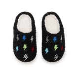 A pair of black fuzzy slip-on slippers with a white sherpa lining and colorful embroidered lightning bolts and checkered patterns, shown on a white background.